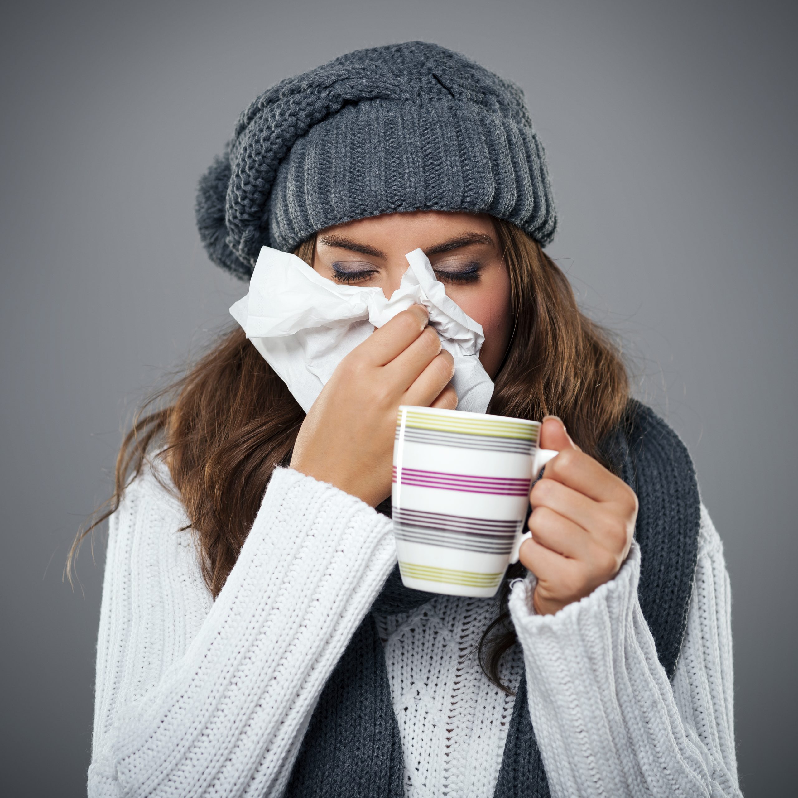 Young woman having flu and blowing her nose at handkerchief